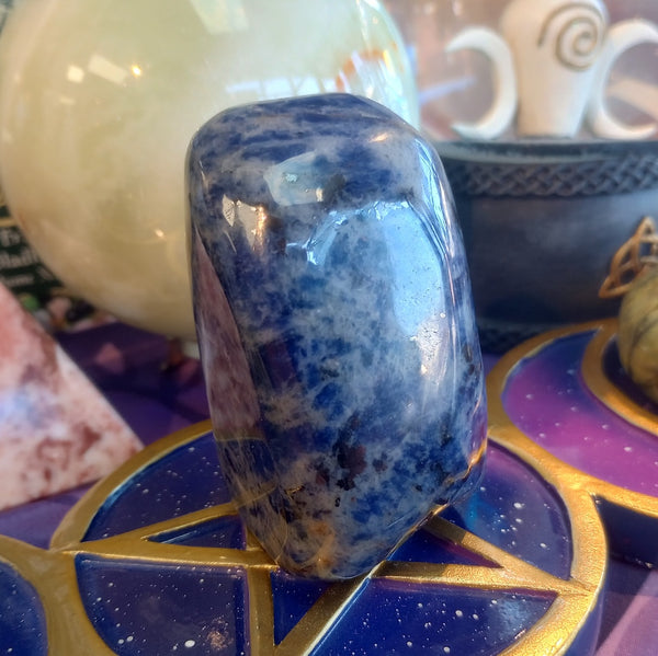 Blue crystal on a purple and gold decorative stand with blurred background