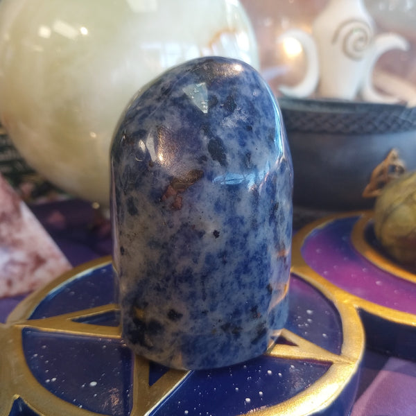 Blue and white speckled stone on a purple and gold tarot card